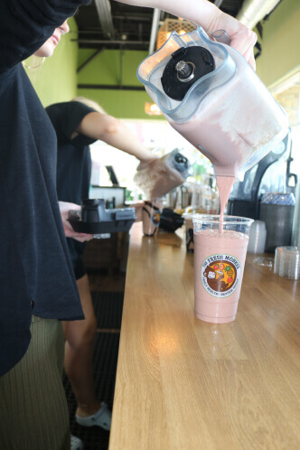a Fresh Monkee barista pouring a strawberry smoothie into a cup
