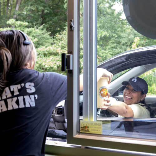 a happy customer collecting her order at the Fresh Monkee drive through